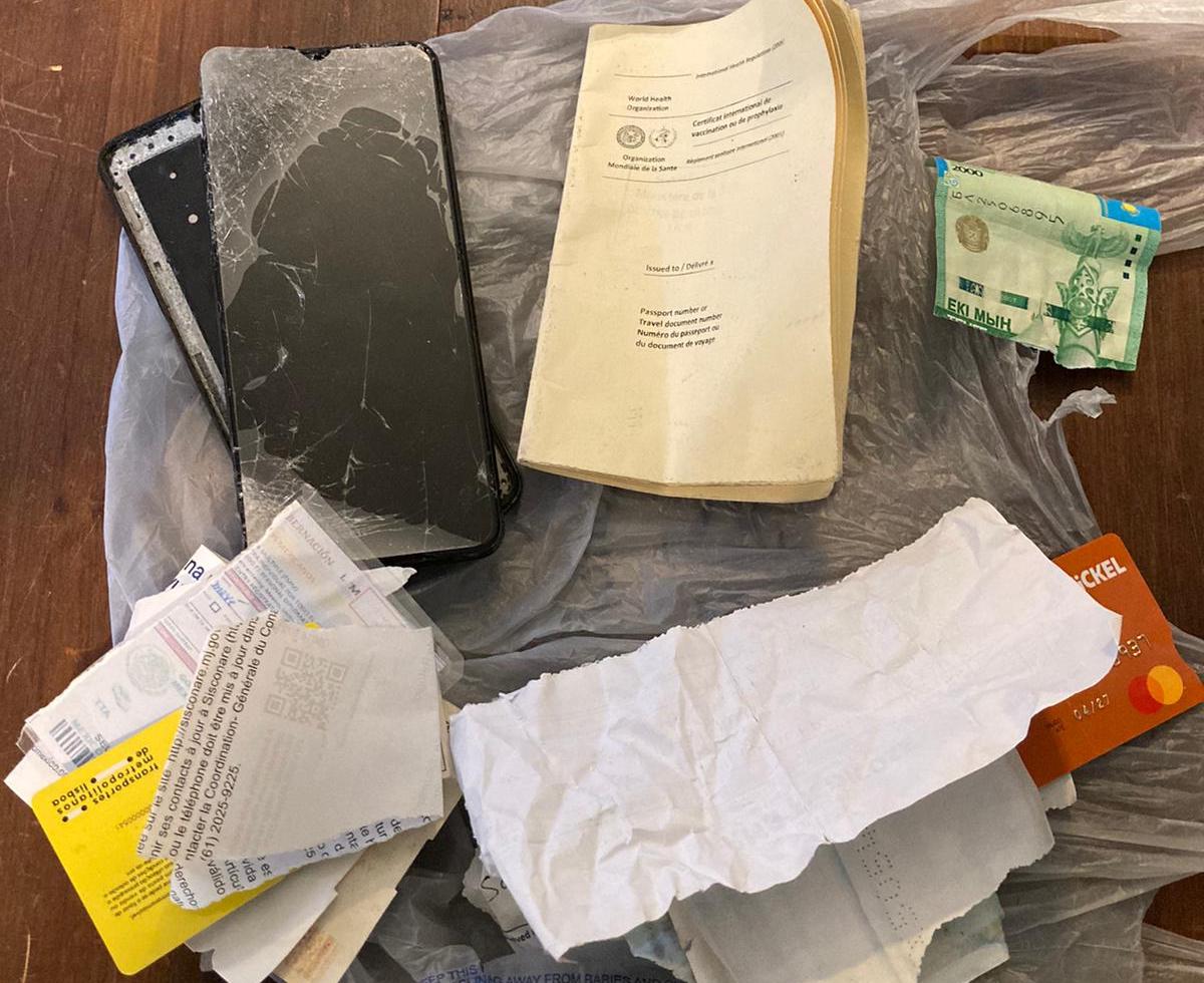 A collection of documents, money, and a damaged smartphone.