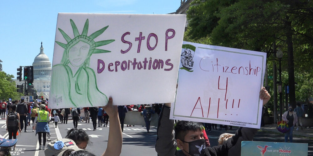 An individual holding a sign that says "Stop Deporations."