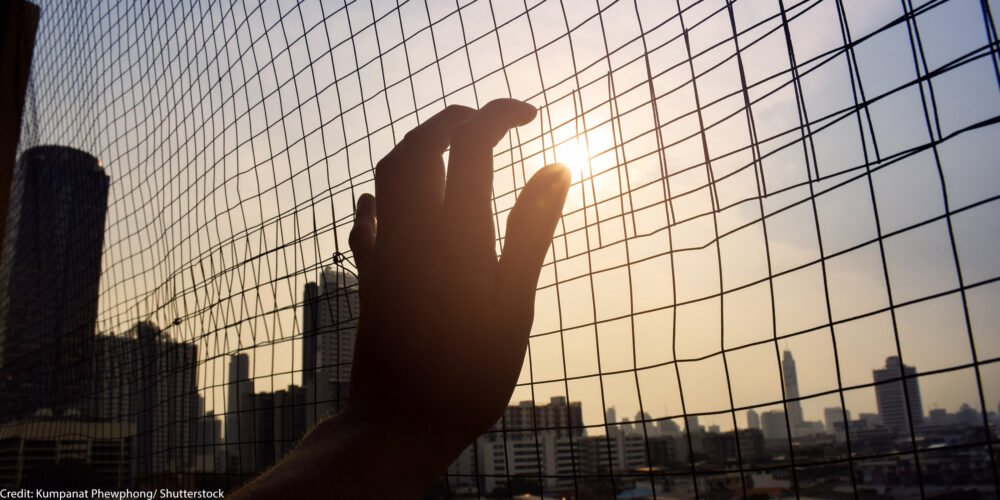A hand holding on to a gate.